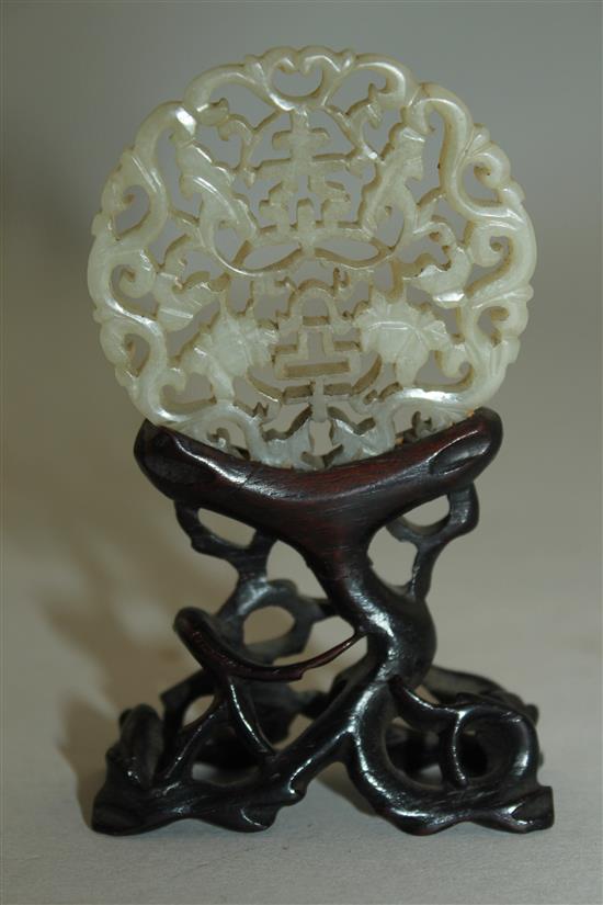 A Chinese celadon jade plaque, 18th / 19th century, 5.3cm, glued to a rosewood stand, overall height 9.5cm